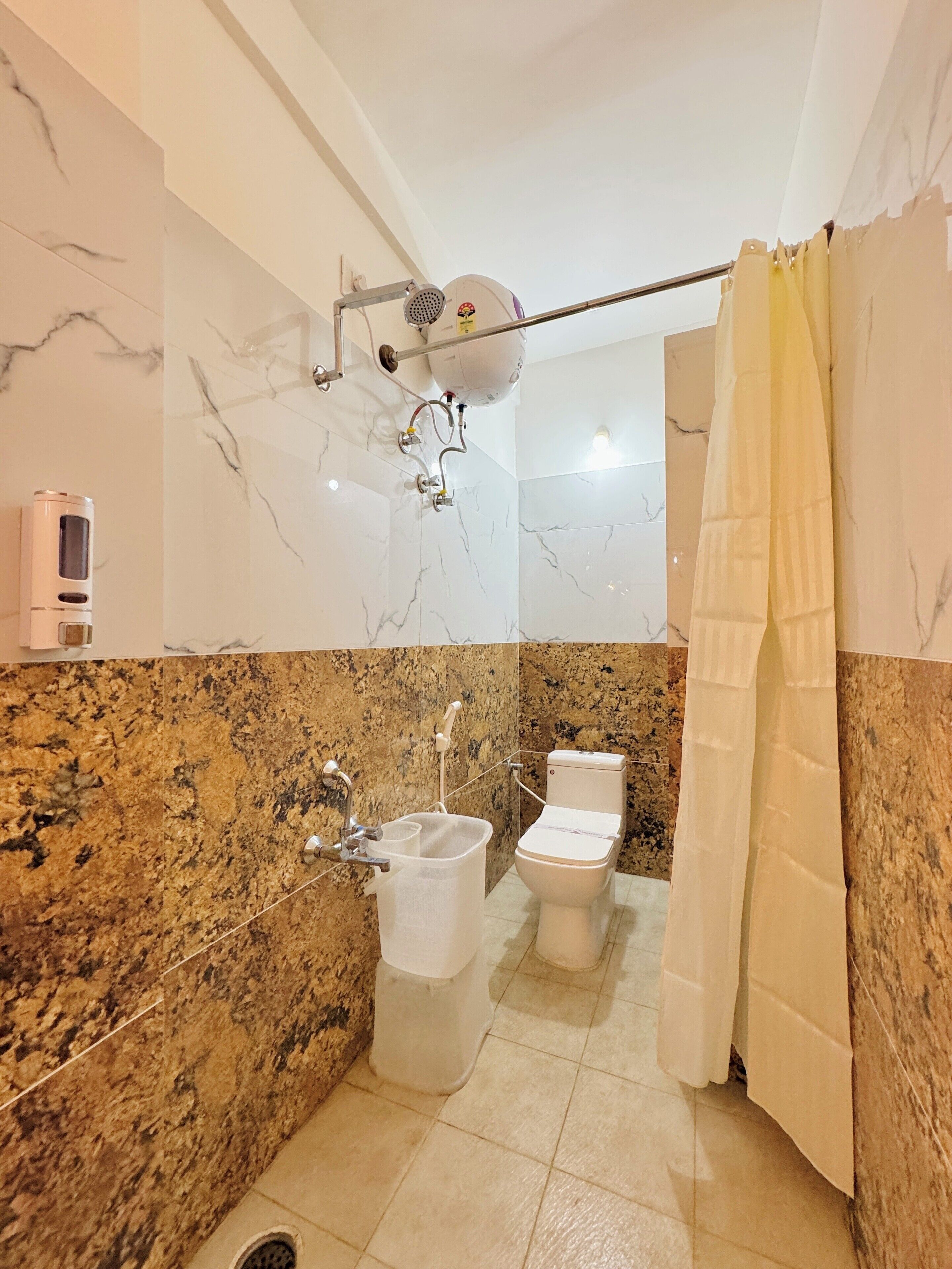 Ein Badezimmer mit Marmorwand, einer Dusche, einer Toilette und einem Waschbecken.