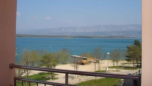 Un balcón con vistas a un lago, árboles y montañas distantes.