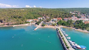 Un pueblo costero con un puerto deportivo, playas de arena y edificios residenciales.