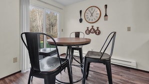 A dining area with a round table and four chairs, a wall clock, and a set of cutlery mounted on the wall. - Quiet 2BR/2BA Olympia townhome on acreage near downtown, Capitol, workspace, garage parking (Olympia)