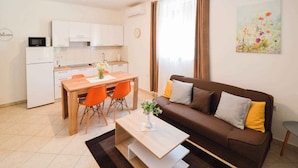 A compact living space with a kitchenette, a dining area, and a sofa. - Apartments in Stinjan/istrien 8432 (Pula)