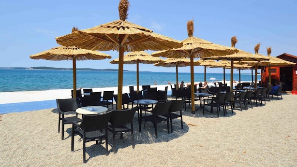 A beachside café with outdoor seating and umbrellas, overlooking the sea. - Apartments in Stinjan/istrien 8432 (Pula)