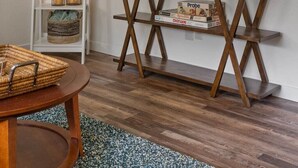 Ein Wohnzimmer mit Flachbildfernseher auf einem Holz-TV-Schrank, einem weißen Regal mit Dekoration und einem runden Couchtisch aus Holz.