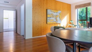 Un intérieur moderne avec un mur d’accent en bois, un coin repas doté d’une table ronde et une vue sur la verdure à l’extérieur.