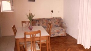Un comedor con una mesa y sillas, un sofá y un ventanal pequeño.