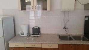 Una cocina con encimera de granito, cafetera, tostadora, lavamanos y armarios de madera.