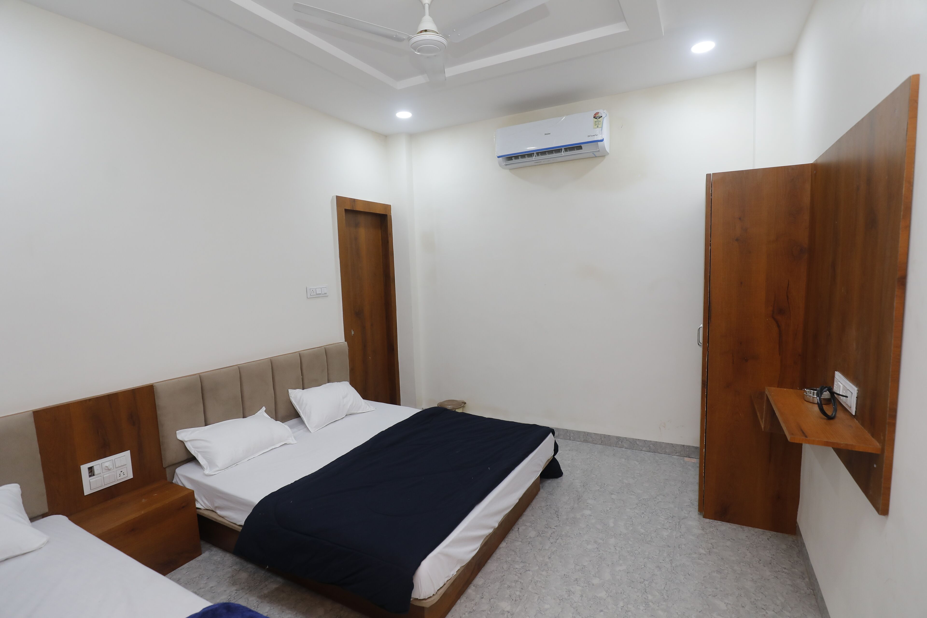 A bedroom with a bed, bedside tables, a wardrobe, an air conditioning unit, and a ceiling fan.
