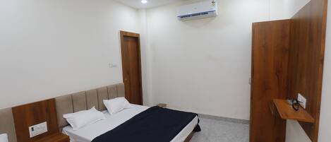 A bedroom with a bed, bedside tables, a wardrobe, an air conditioning unit, and a ceiling fan.
