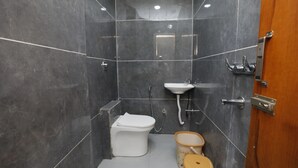 A compact bathroom with a toilet, bidet, and sink. - Hotel Garima (Ujjain)