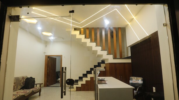 A modern interior with a staircase, a sofa, and a desk area. - Hotel Garima (Ujjain)