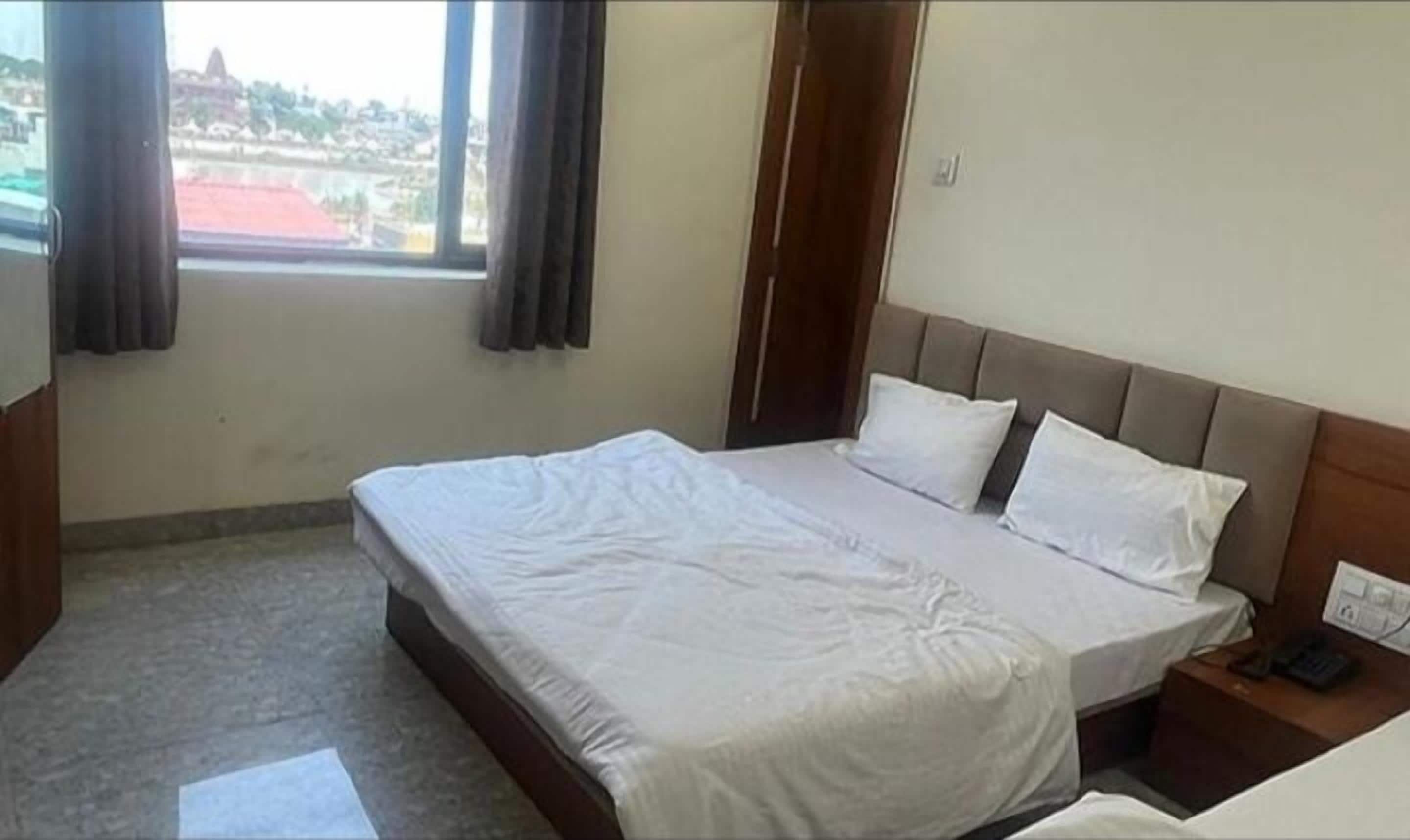 A hotel room with a bed, a nightstand, and a window with curtains.
