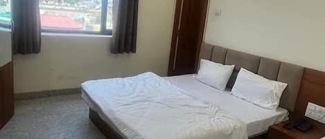 A hotel room with a bed, a nightstand, and a window with curtains.