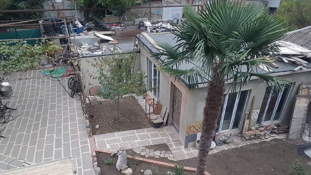 A rooftop garden with a palm tree, a small seating area, and a paved walkway. - Romson Tbilisi (Tbilisi)