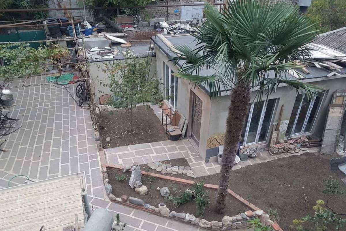 Un jardin sur le toit, agrémenté d’un palmier, d’un petit espace salon et d’une allée pavée.