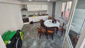 A compact kitchen with a dining area, featuring a round table with chairs, a built-in stove, and cabinets. - Romson Tbilisi (Tbilisi)
