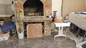 A room with a brick fireplace, a wooden table, and various items scattered around. - Romson Tbilisi (Tbilisi)