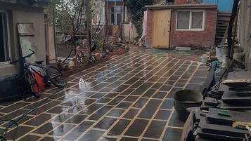 Un patio con suelo de baldosas, una bicicleta y diversos materiales de construcción.