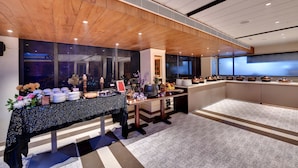 A modern hotel room with a wooden ceiling, a large window, and a buffet setup with plates and flowers. - Click Collection Amritsar (Amritsar)