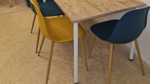 A dining area with a wooden table, yellow and blue chairs, and a sofa with yellow cushions. - Charming condo in pleasant Rabat with WiFi (Temara)