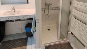 Une salle de bain avec une douche, un lavabo et un miroir.