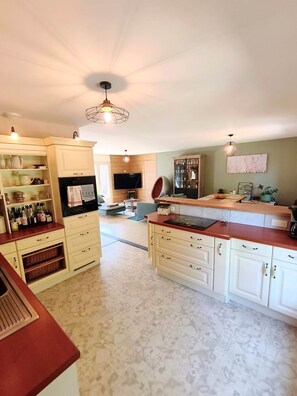 Een ruime keuken met een centraal eiland, inbouwmeubels en een zithoek met een bank en tafel.