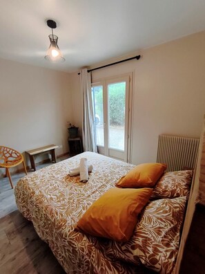 A bedroom with a bed, a chair, a table, and a window with curtains.