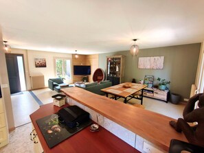 A modern living room with a long wooden table, a comfortable sofa, and a television.