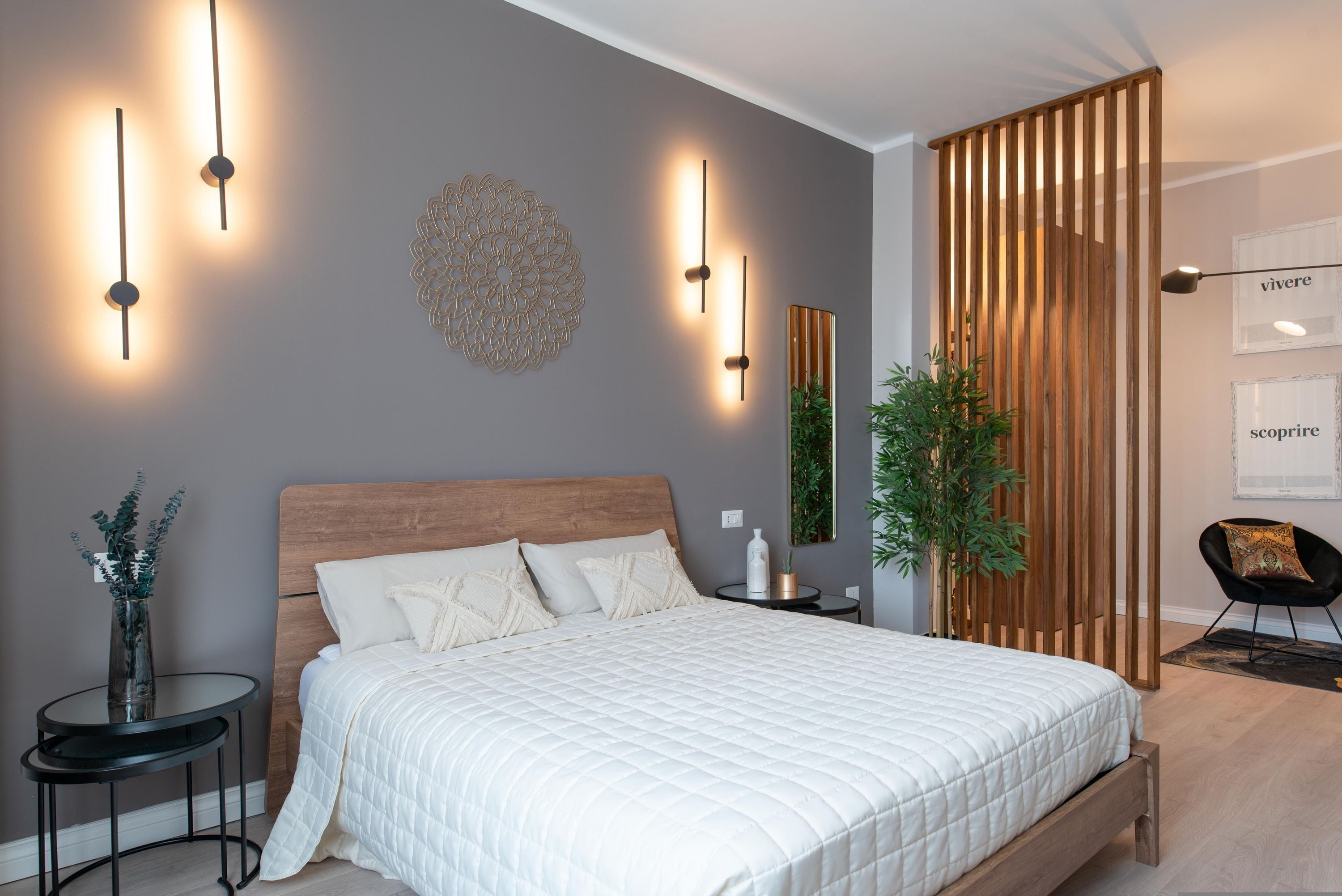Quarto moderno com cama grande, mesas de cabeceira, um objeto decorativo na parede e um painel de madeira.