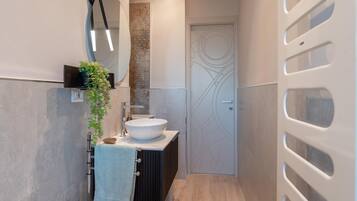 Un bagno moderno con uno specchio rotondo, un lavandino bianco e un portascopevoli.