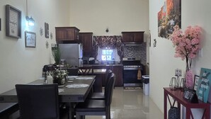 A spacious kitchen with modern appliances, a dining area with a table set for four, and a red console table with decorative items.