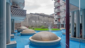 Un patio con una fuente, una piscina y un edificio con balcones.