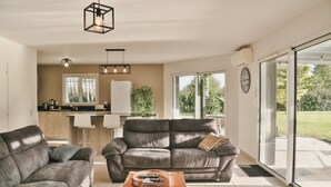 A modern living room with two grey sofas, a wooden coffee table, and a kitchen in the background. - House for 6, swimming pool and garden (Bénesse-Maremne)