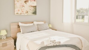 A neatly arranged bedroom with a bed, bedside lamps, a wall-mounted artwork, and a window with curtains. - House for 6, swimming pool and garden (Bénesse-Maremne)