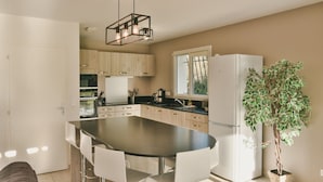 A modern kitchen with a central island, white cabinetry, and a built-in refrigerator. - House for 6, swimming pool and garden (Bénesse-Maremne)
