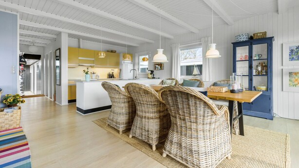 A spacious kitchen with high ceilings and white cabinetry, a dining area with wicker chairs, and a blue cabinet with glassware. - Gorgeous home in Ebeltoft with sauna (Ebeltoft)
