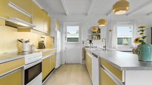 A kitchen with yellow cabinets, a white stove, and a window overlooking a balcony. - Gorgeous home in Ebeltoft with sauna (Ebeltoft)