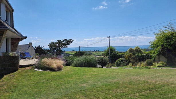 A residential property with a lawn, a large tree, and a view of the sea. - Elegance on the bay, modern apartment with garden and sea view (Crozon)