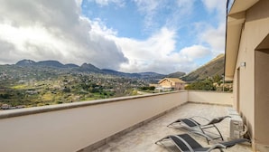 A balcony with a view of a mountainous landscape, a chair, and a small table. -  Home Sweet Home (Monreale)
