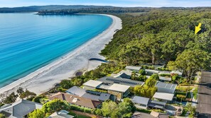 A coastal property with a beach, houses, and dense forest.