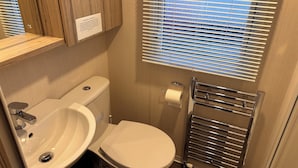 A small bathroom with a toilet, sink, and towel rack. - 3br-sleeps6-parking-pool-nearbeach&skegness (Skegness)
