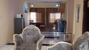 Una sala de estar con dos sillones ornamentados, una mesa de centro y un televisor.