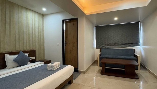 Une chambre d’hôtel moderne avec un grand lit, un banc, un ventilateur de plafond et une fenêtre donnant sur un beau paysage.