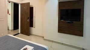 Une chambre moderne avec un grand lit, un téléviseur à écran plat fixé sur un panneau en bois et un climatiseur installé au plafond.