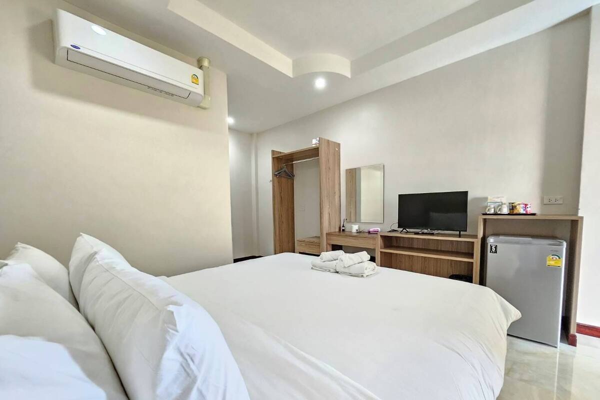 A hotel room with a bed, a TV, a mini-fridge, and a wardrobe.