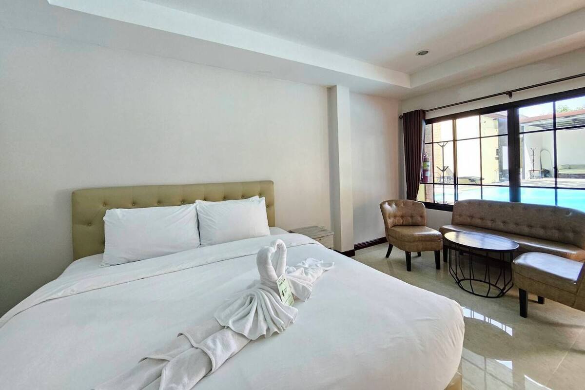 A hotel room with a large bed, a sofa, a chair, and a small table.