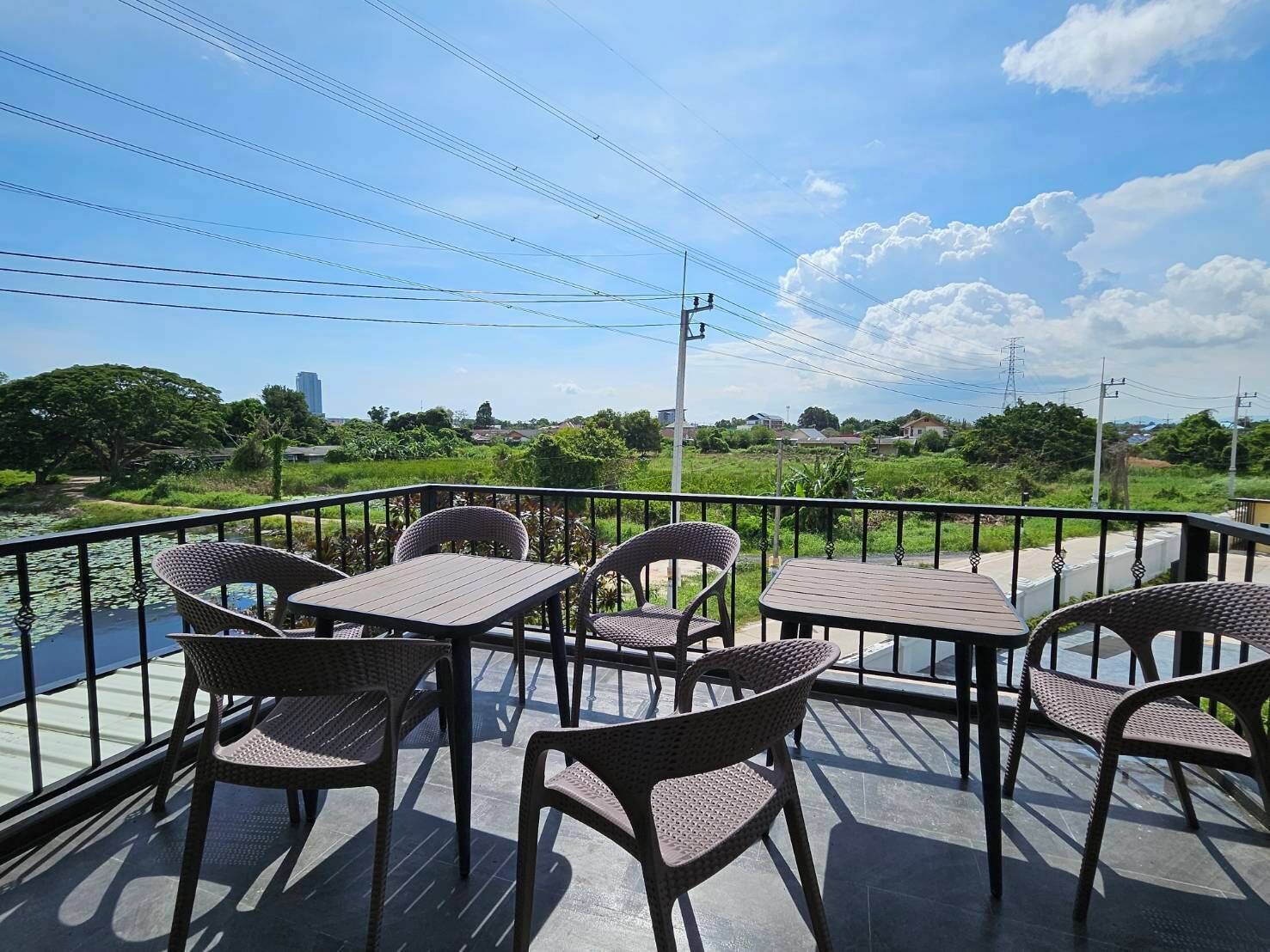 A terrace with wicker furniture and a view of a river and greenery.