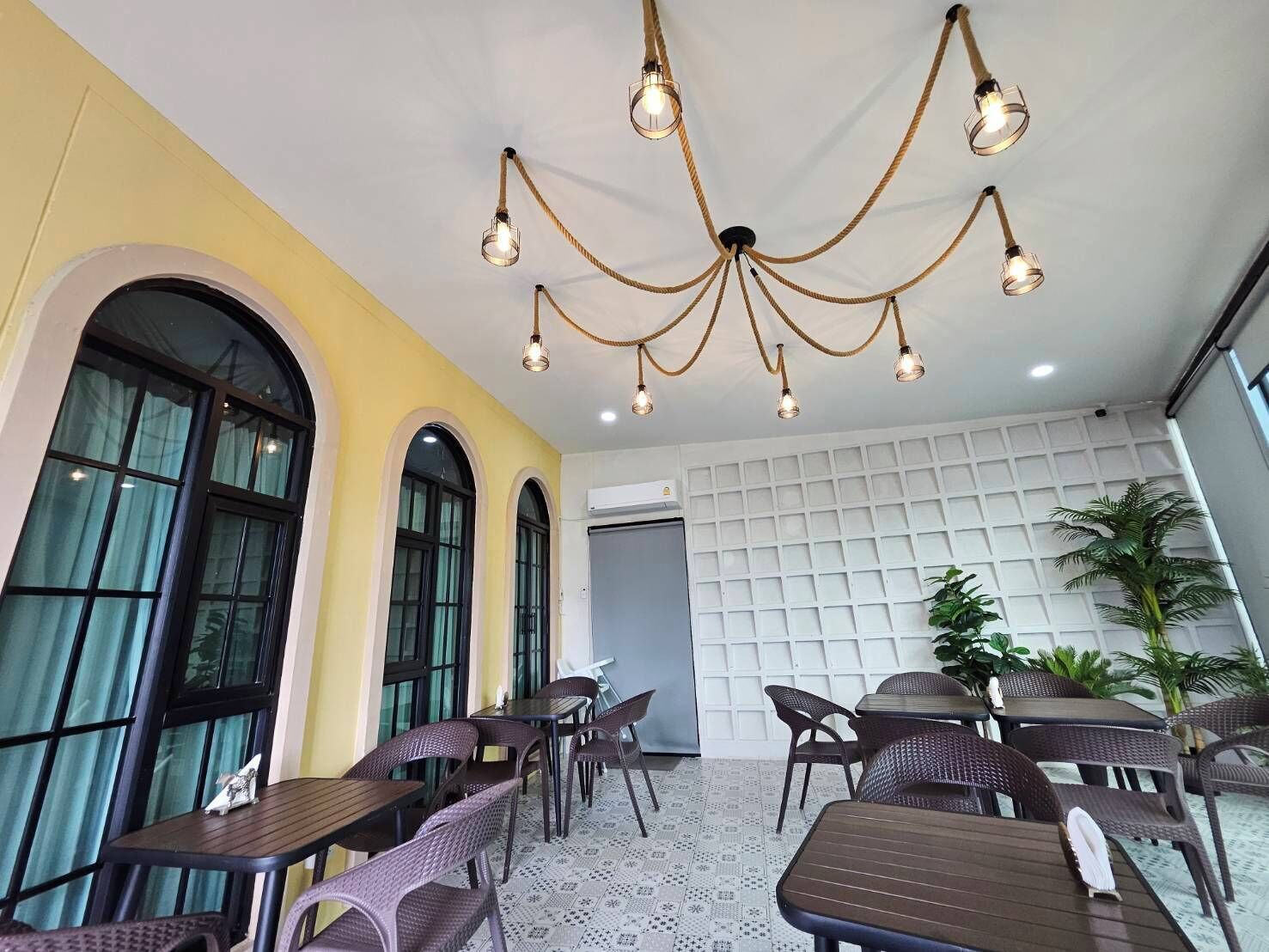 Un interior de restaurante con una araña, mesas, sillas y un suelo estampado.