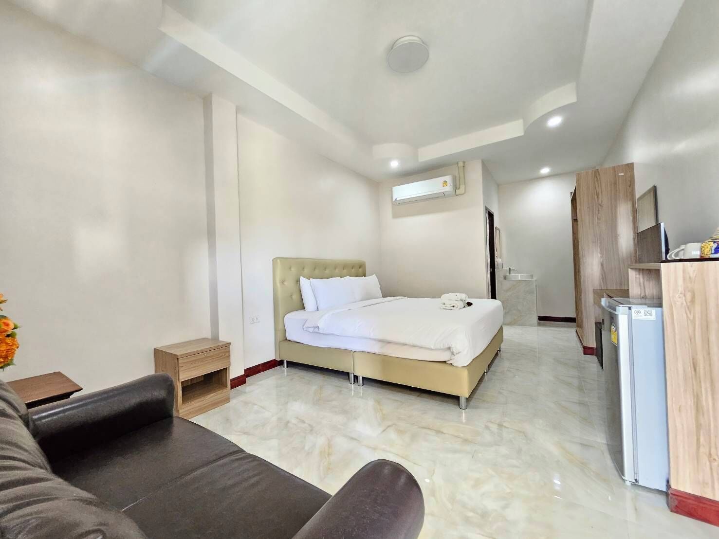 Habitación de hotel con cama, escritorio, silla, una mesita y refrigerador.