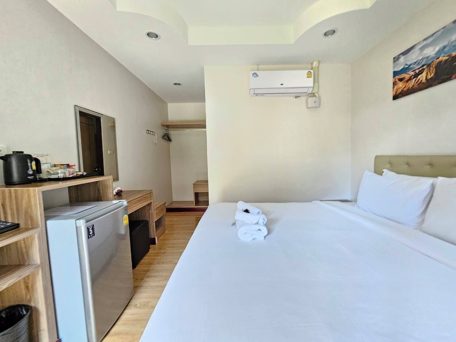 Une chambre d’hôtel équipée d’un lit, d’un bureau avec une machine à café, d’un mini-réfrigérateur, d’un climatiseur et d’un tableau au mur.