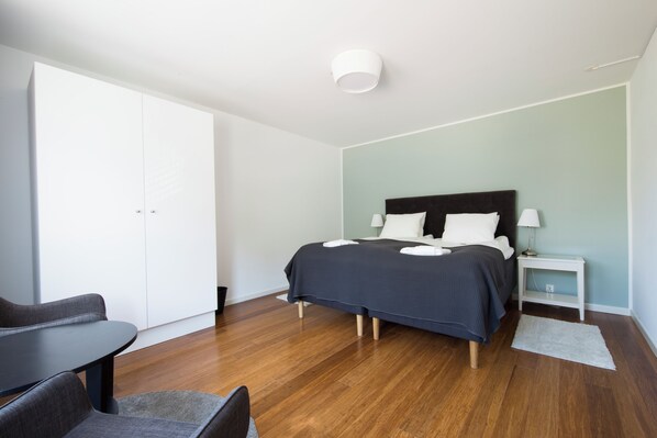 A modern bedroom with a bed, bedside table, and a chair. - Continental Apartment Hotels Sollentuna (Sollentuna)